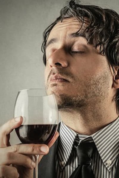 Man die ruikt aan een glas rode wijn met gesloten ogen