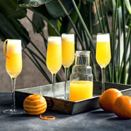 Mimosa's in Champagne glazen met wat sinaasappels eromheen